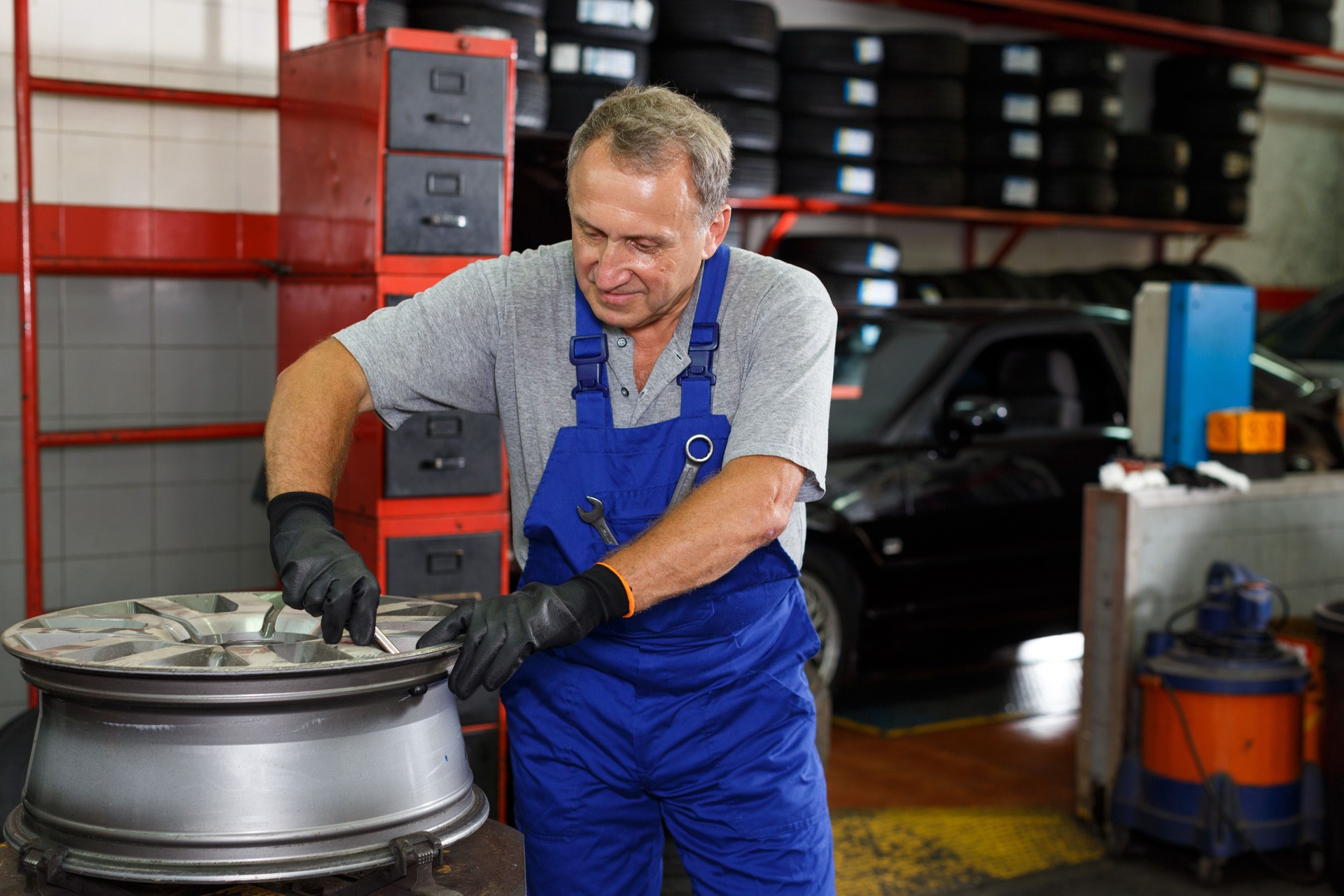 Mechanician restoring tire and disc of car wheel